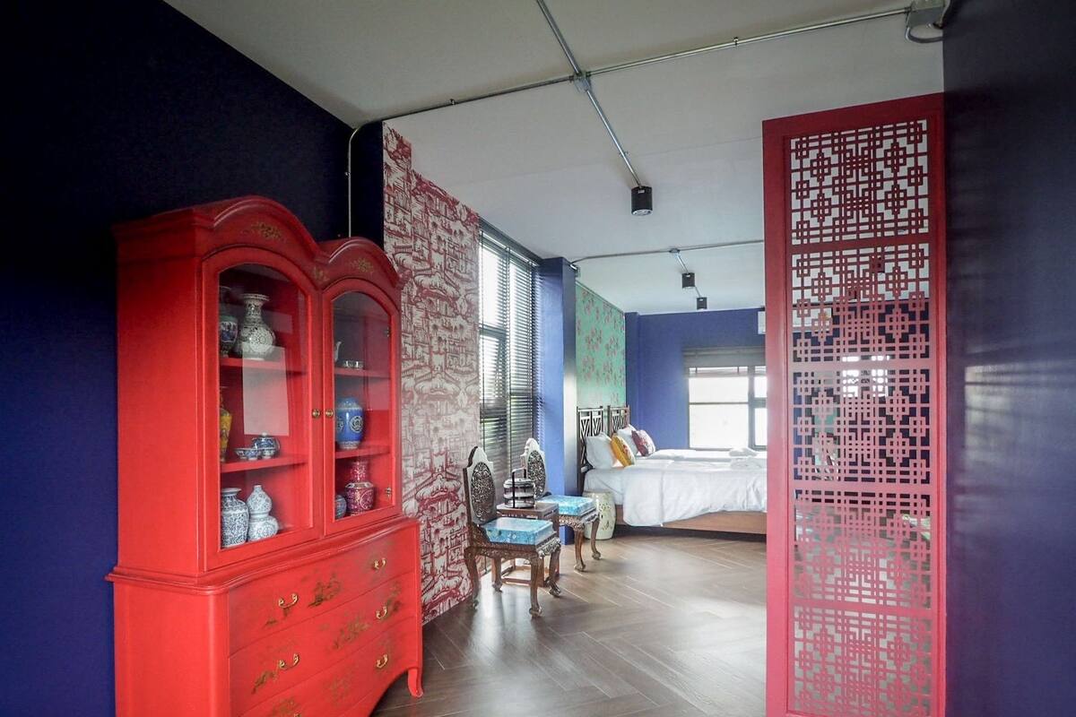 A room with a red cabinet, a bed, and a decorative screen.