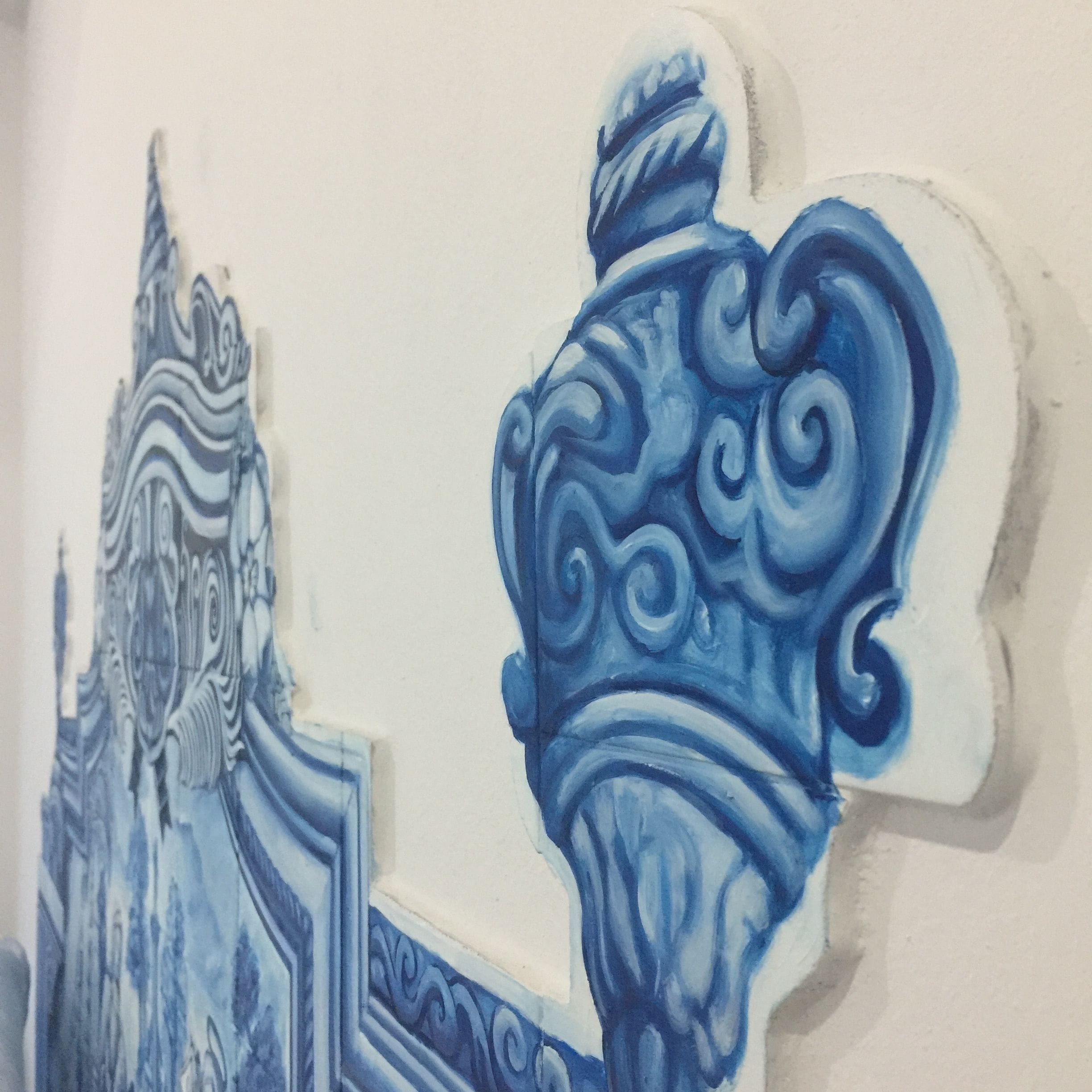 Eine Wand mit blauen architektonischen Ornamenten, darunter ein Gebäudefassadenteil und eine Zierurne.