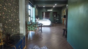 A hotel room with a bed, a seating area with chairs, a small table, and a decorative rug. - WIW Minihotel (Bangkok)