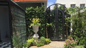 A garden with a gravel path, a decorative urn, and a black metal gate. - WIW Minihotel (Bangkok)