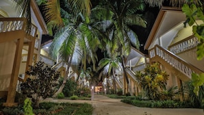 A corridor lined with palm trees and a pathway leading to a building with balconies. - Laguna Beach (Morondava)