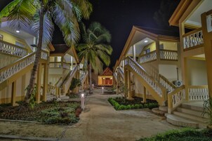 Un hotel con edificios de varios pisos, un patio central y palmeras.