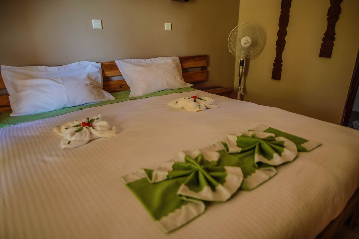 A neatly made bed with white linens and a green decorative pillow.