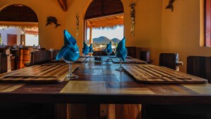 A long wooden dining table with blue napkins, wine glasses, and cutlery. - Laguna Beach (Morondava)