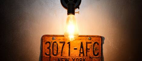 Luminária fixada na parede com placa de carro estilo vintage com a inscrição "3071-AFC NEW YORK".