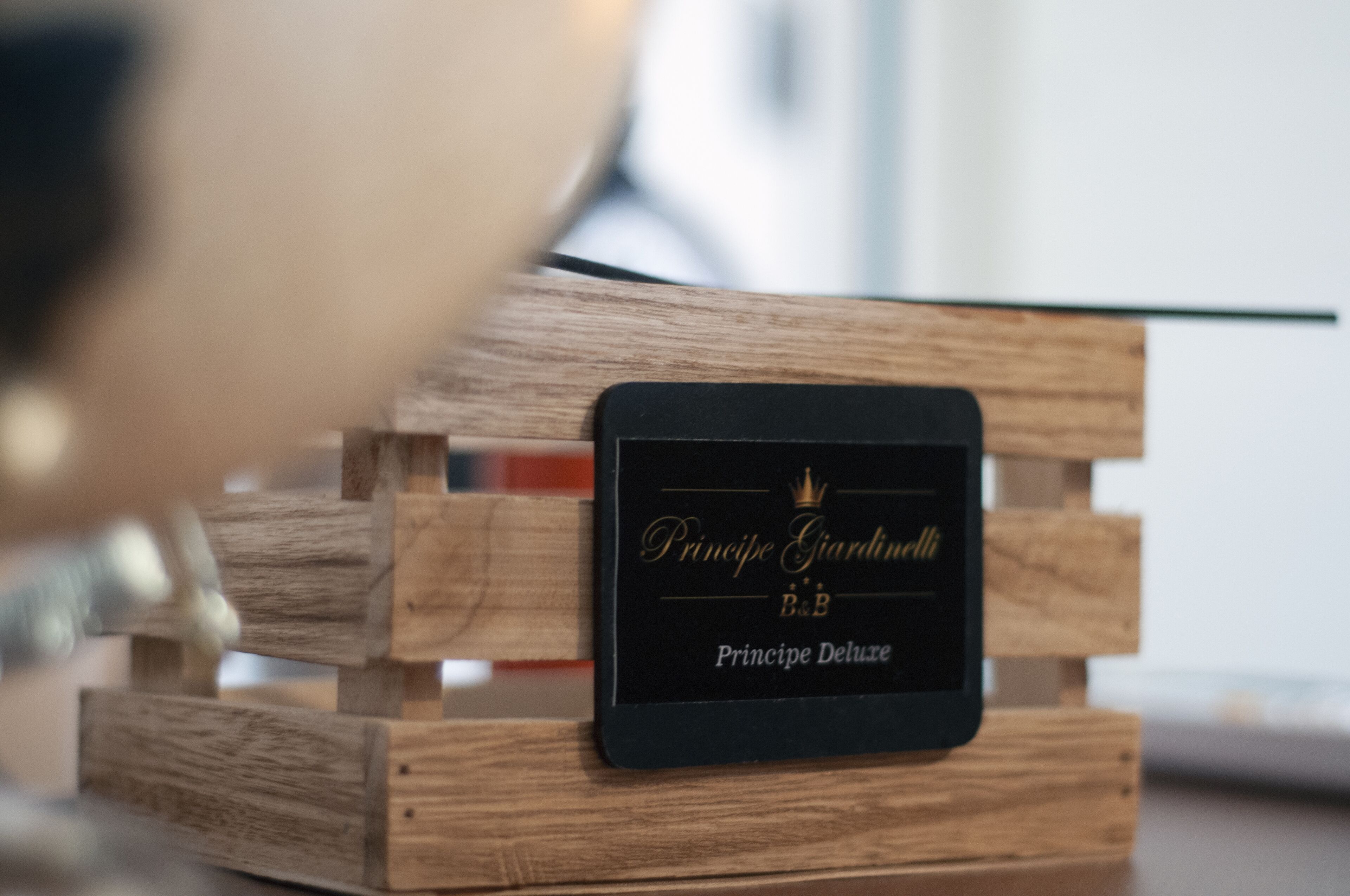 Une caisse en bois avec une étiquette noire indiquant « Princeje Giardini B&B » et « Princeje Deluxe ».