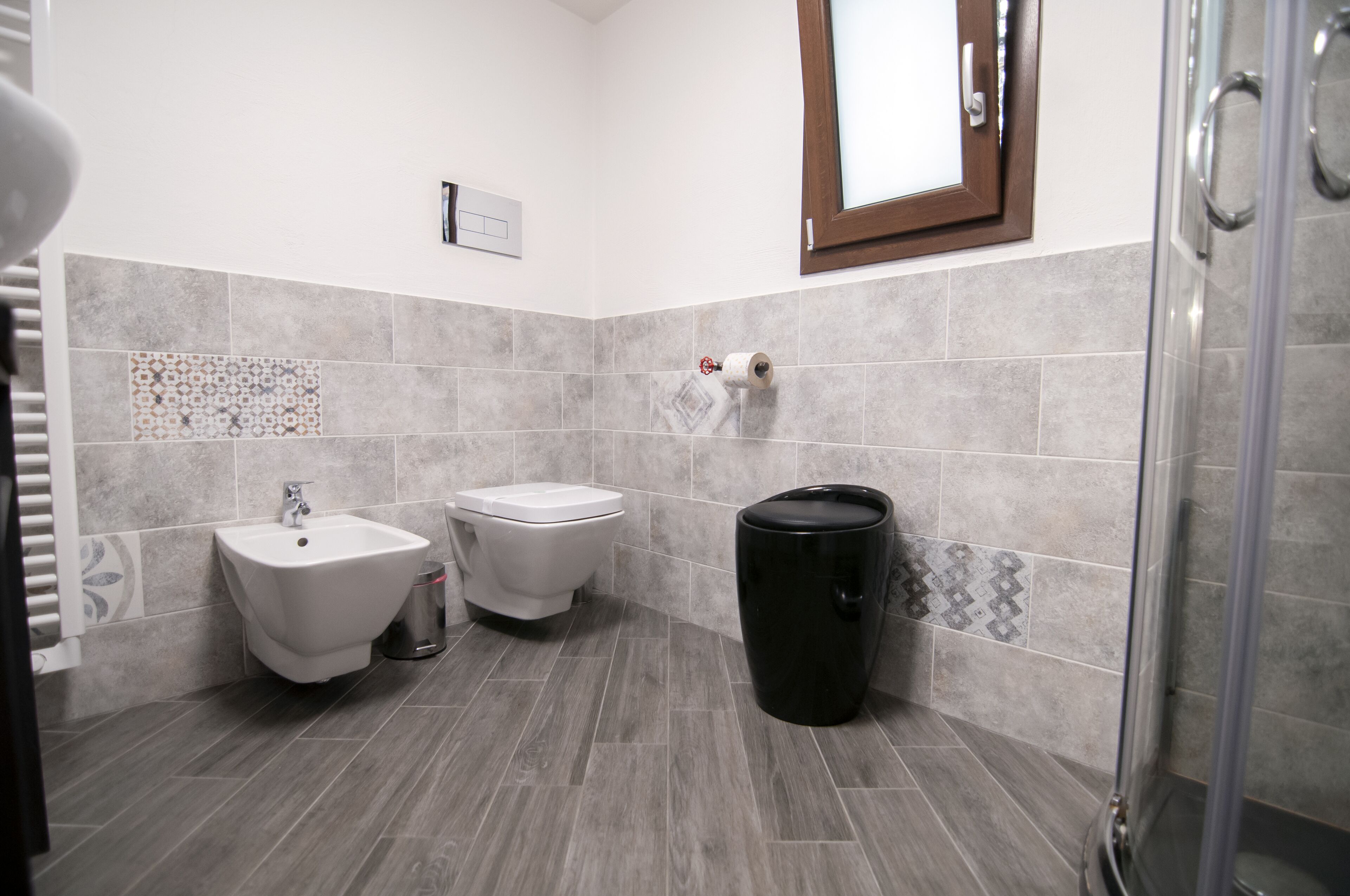 Une salle de bain moderne équipée d’un bidet, de toilettes et d’une poubelle.