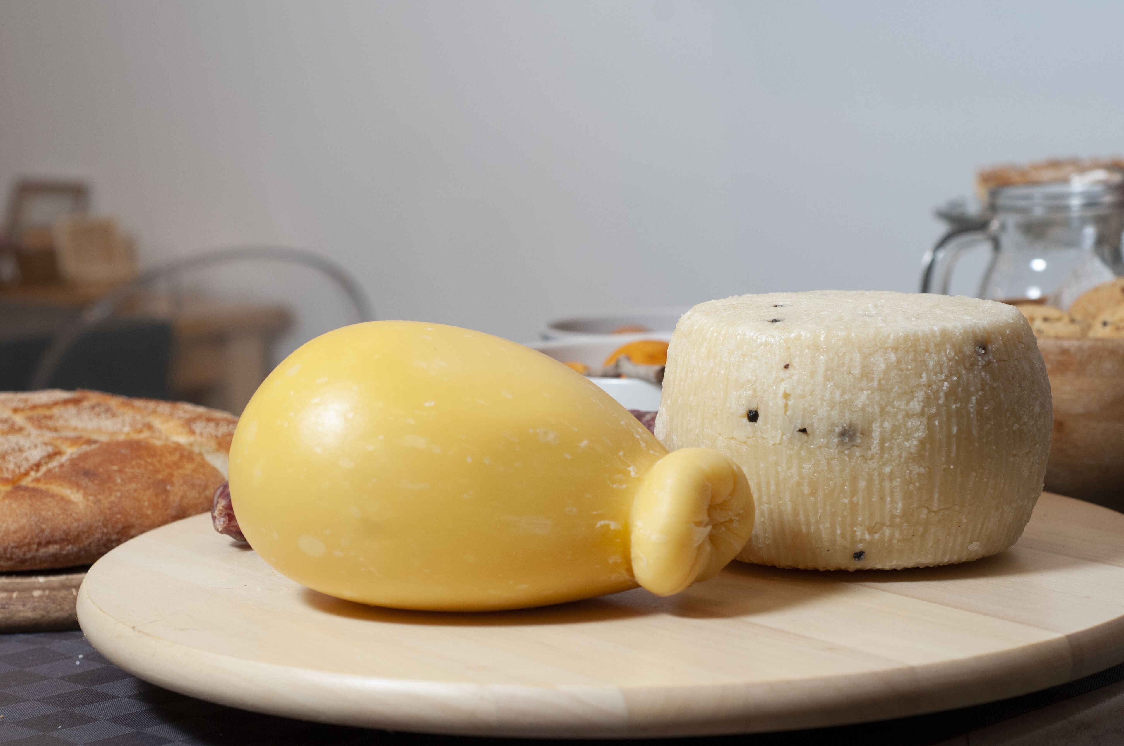 A cheese wheel and a yellow cheese on a wooden board.
