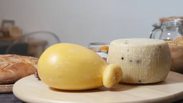 A cheese wheel and a yellow cheese on a wooden board.