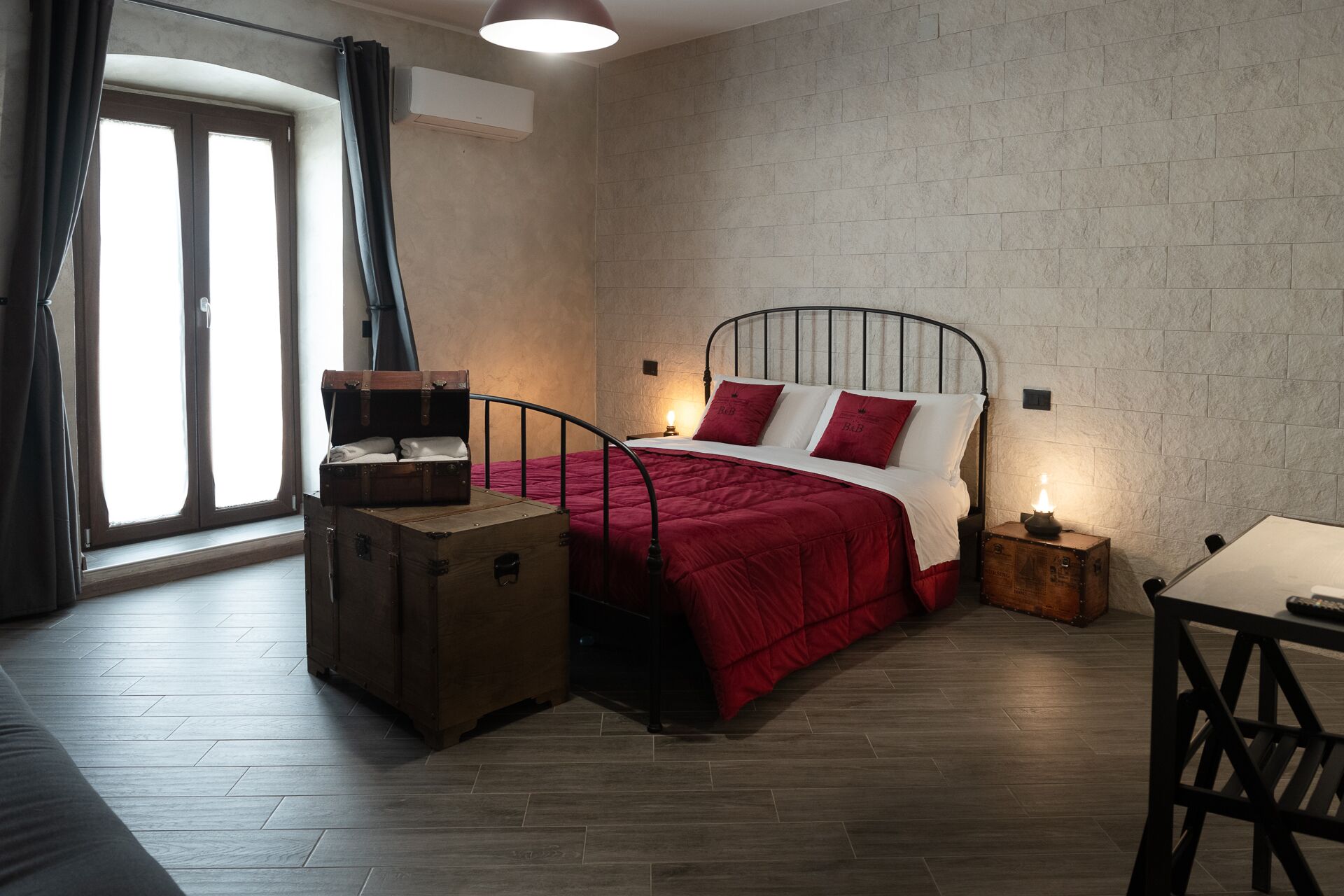 A bedroom with a bed, a suitcase, a nightstand, and a table.
