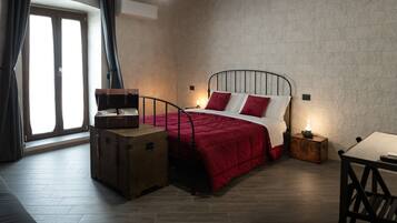 A bedroom with a bed, a suitcase, a nightstand, and a table.