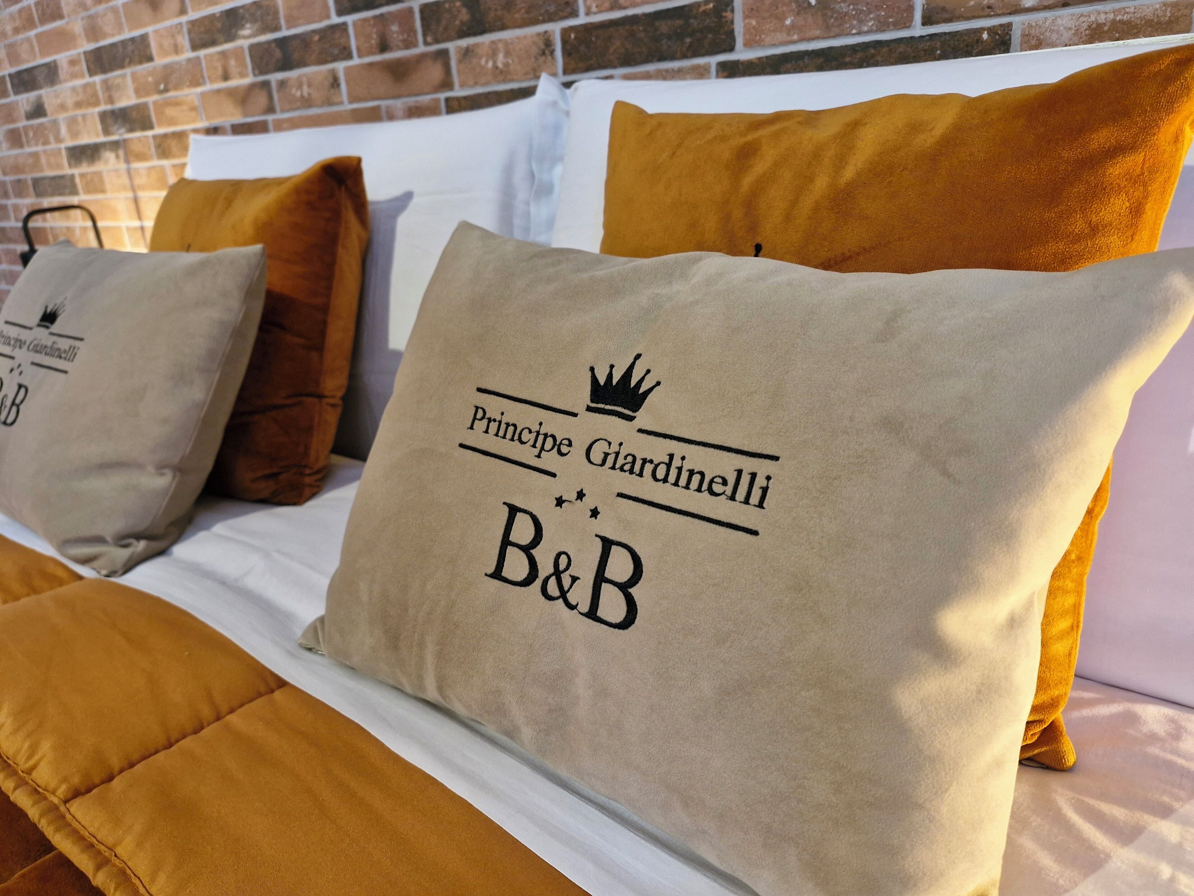 A bed with beige pillows featuring a logo and text.