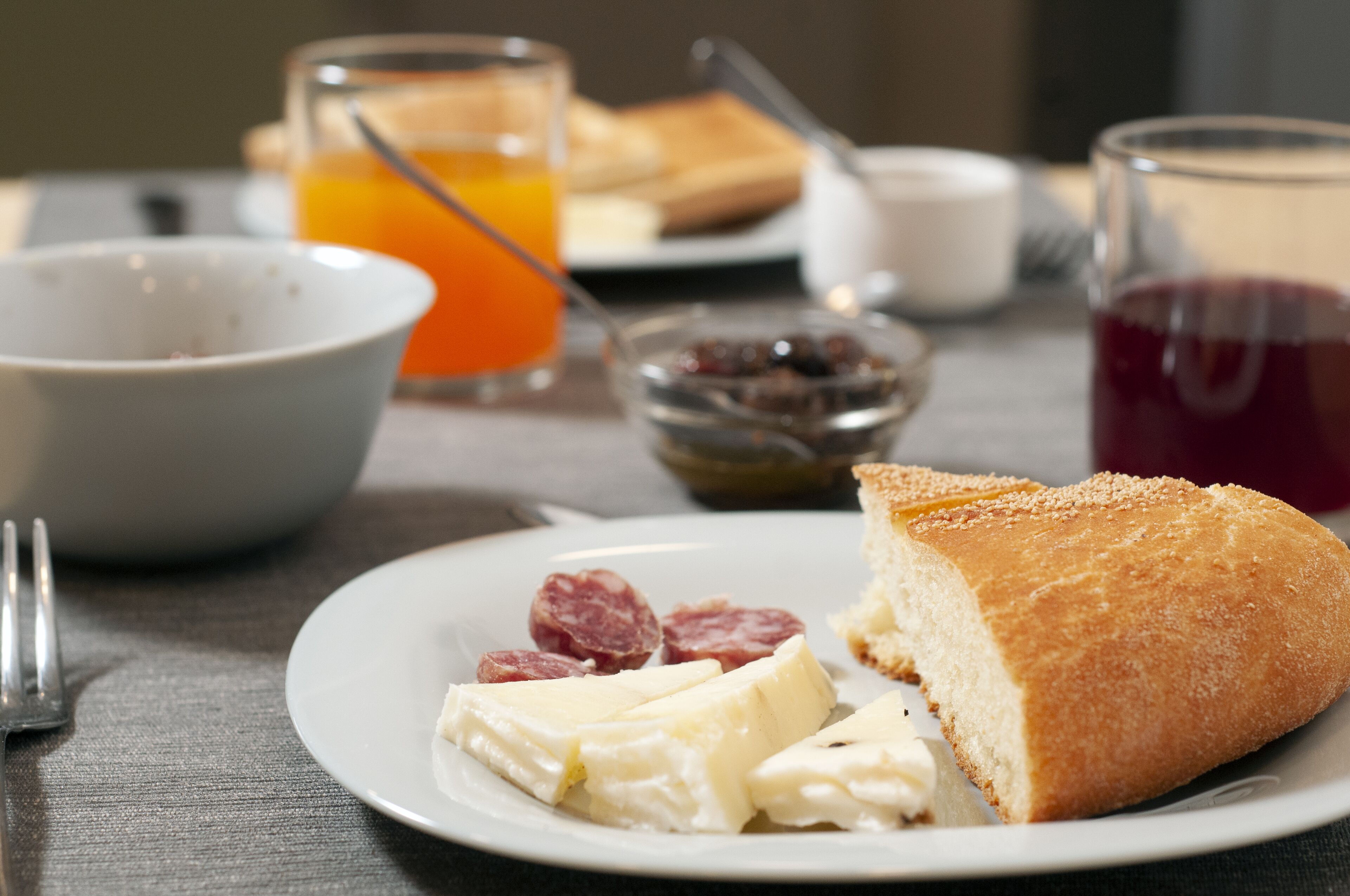 Desayuno con un plato de queso, pan y un vaso de jugo de naranja.