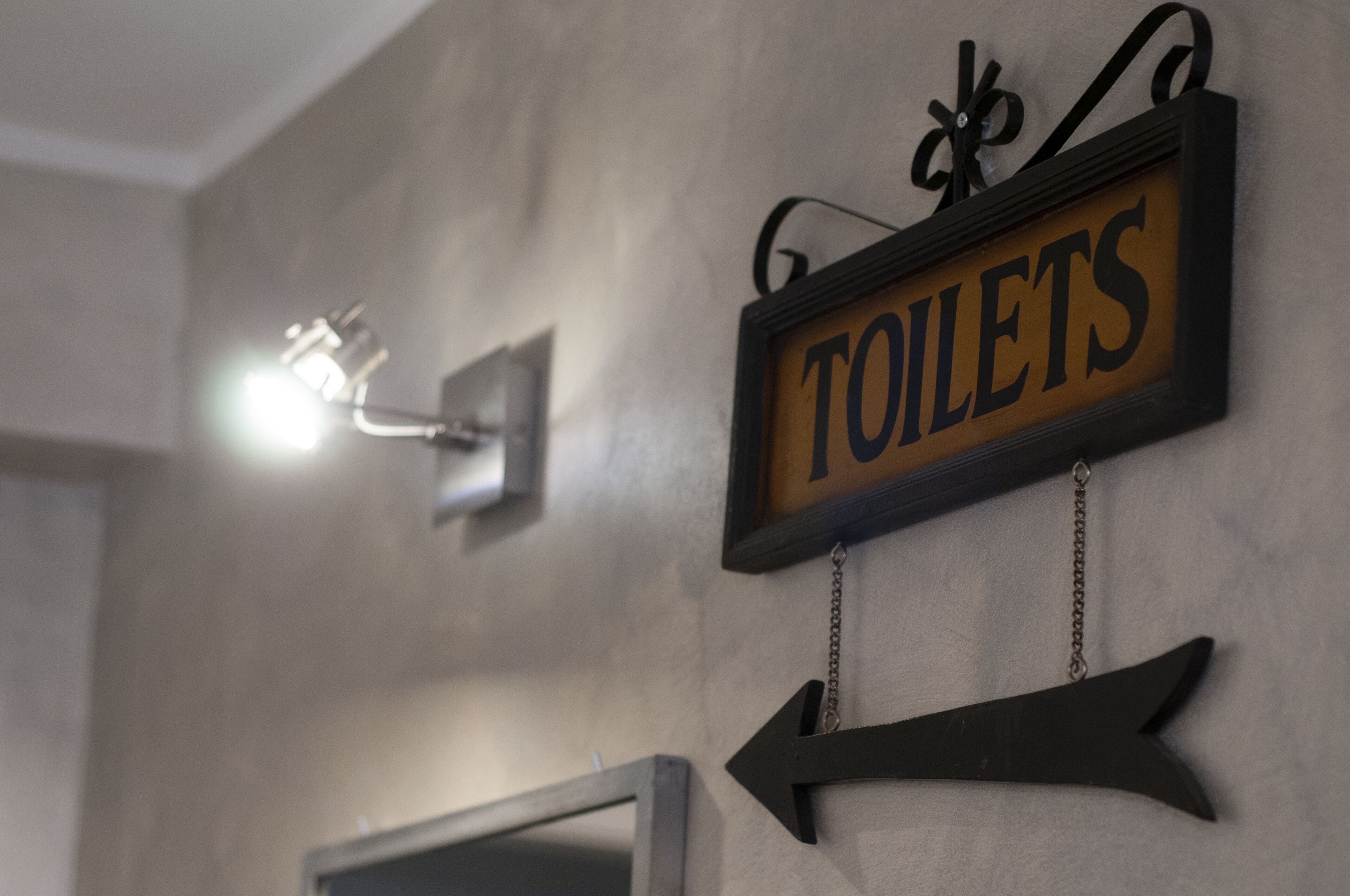 A sign for toilets with an arrow pointing to the left.
