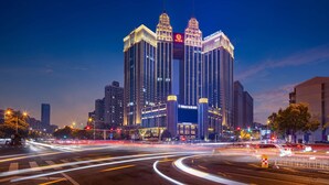 A modern hotel with a distinctive twin-tower design, featuring illuminated signage and a prominent entrance. - Worldhotel Grand Jiaxing Hunan (Changsha)