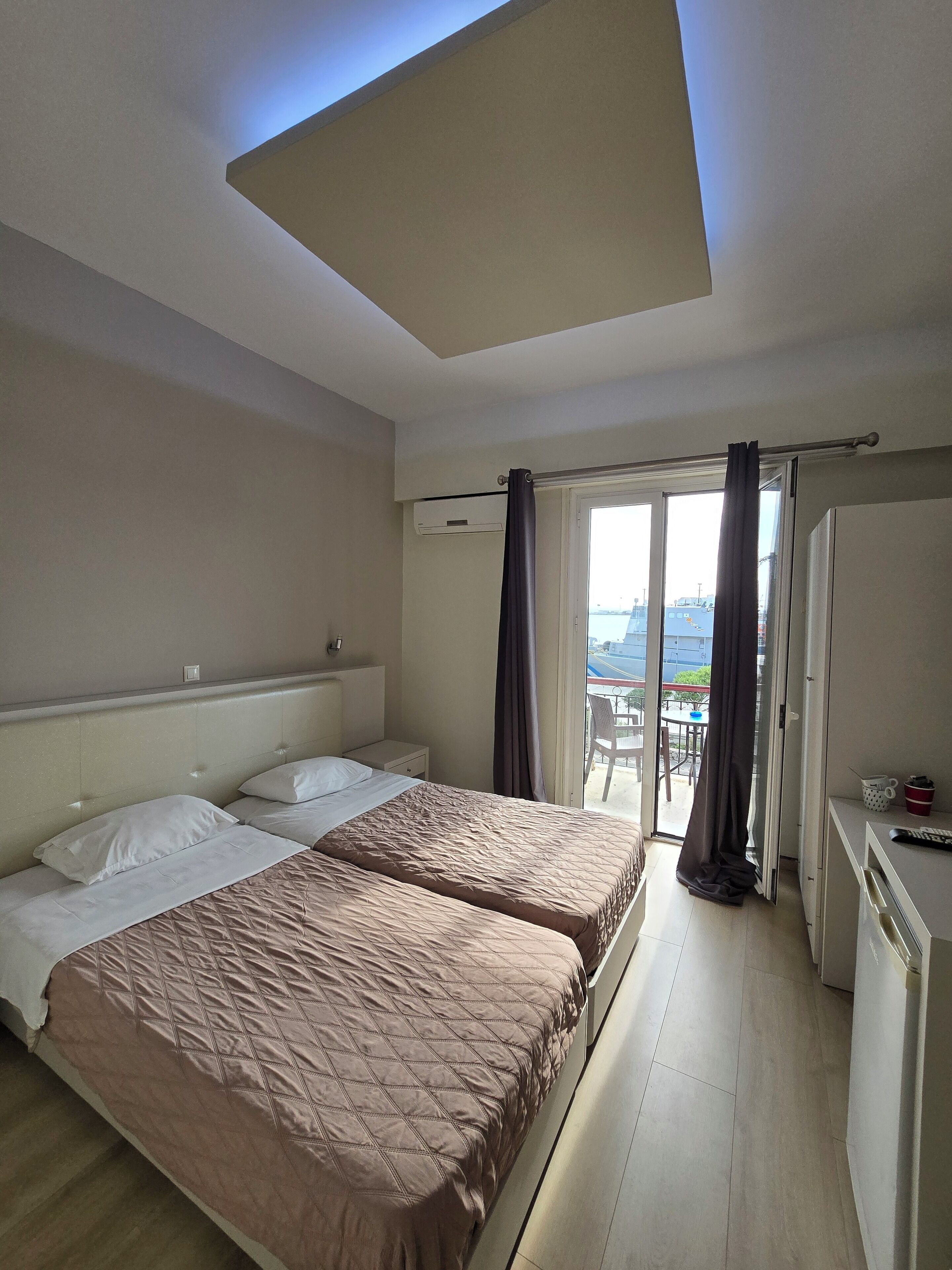 Une chambre d’hôtel avec deux lits, un petit bureau et un balcon avec vue.