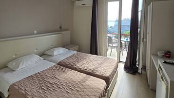 Une chambre d’hôtel avec deux lits, un petit bureau et un balcon avec vue.
