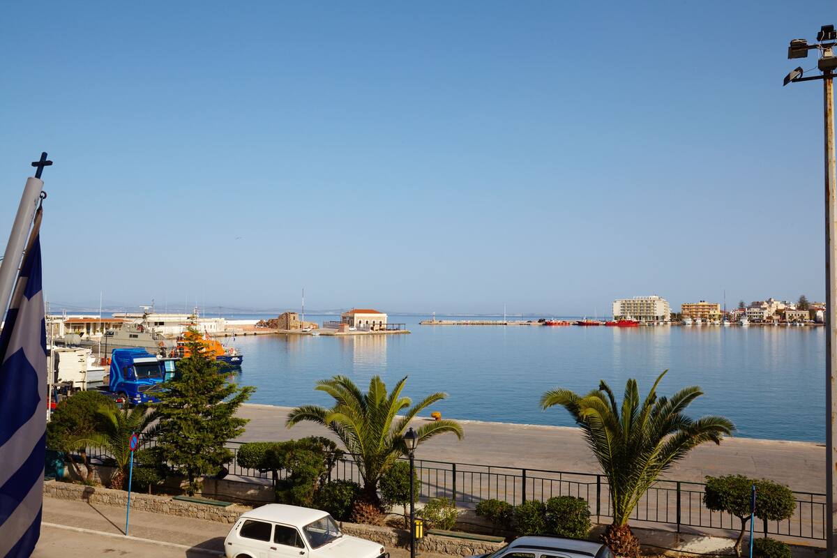 Una marina con barche, un'auto bianca e un camioncino blu.