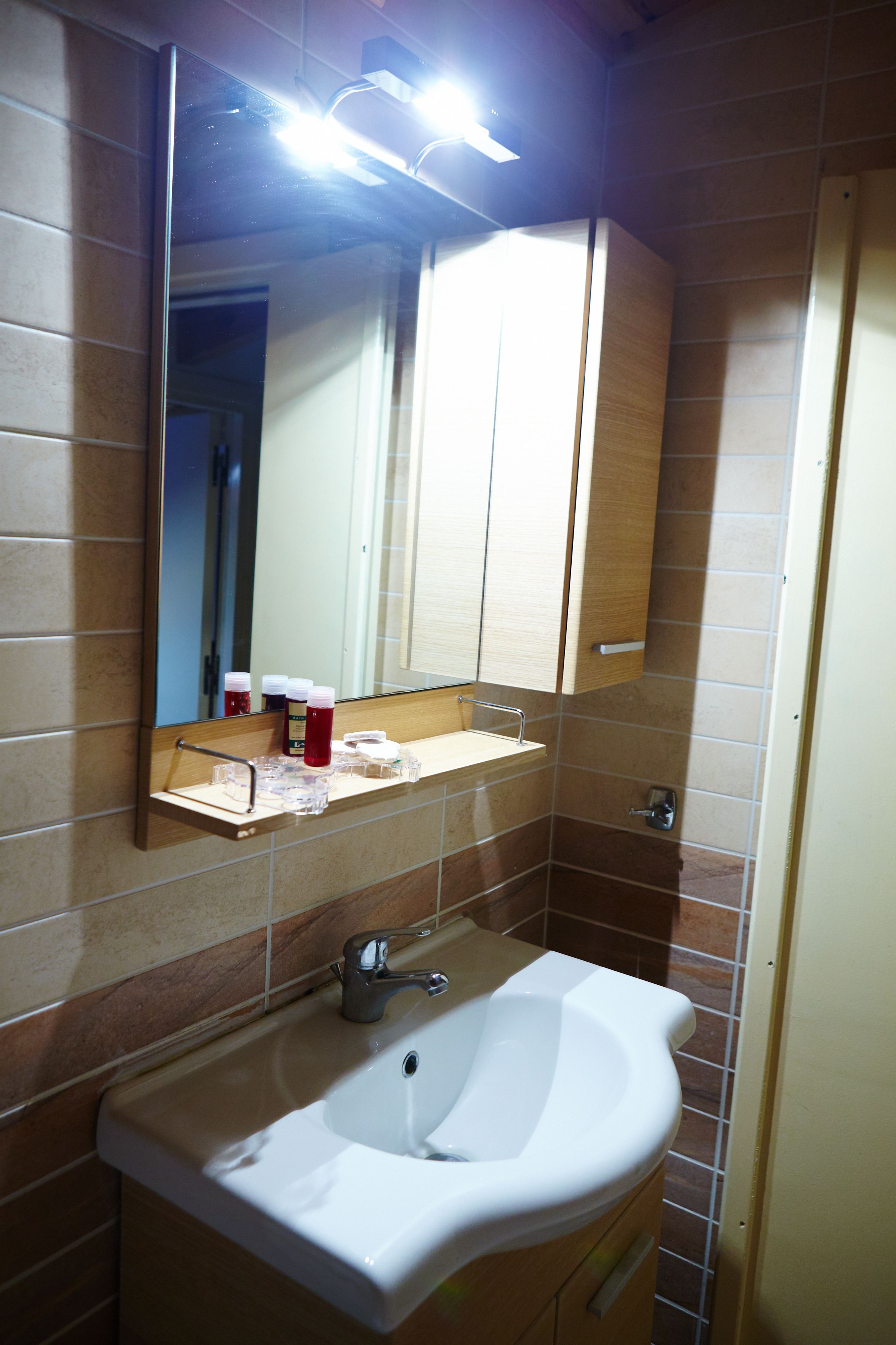 A bathroom with a white sink, mirror, and wooden cabinet.