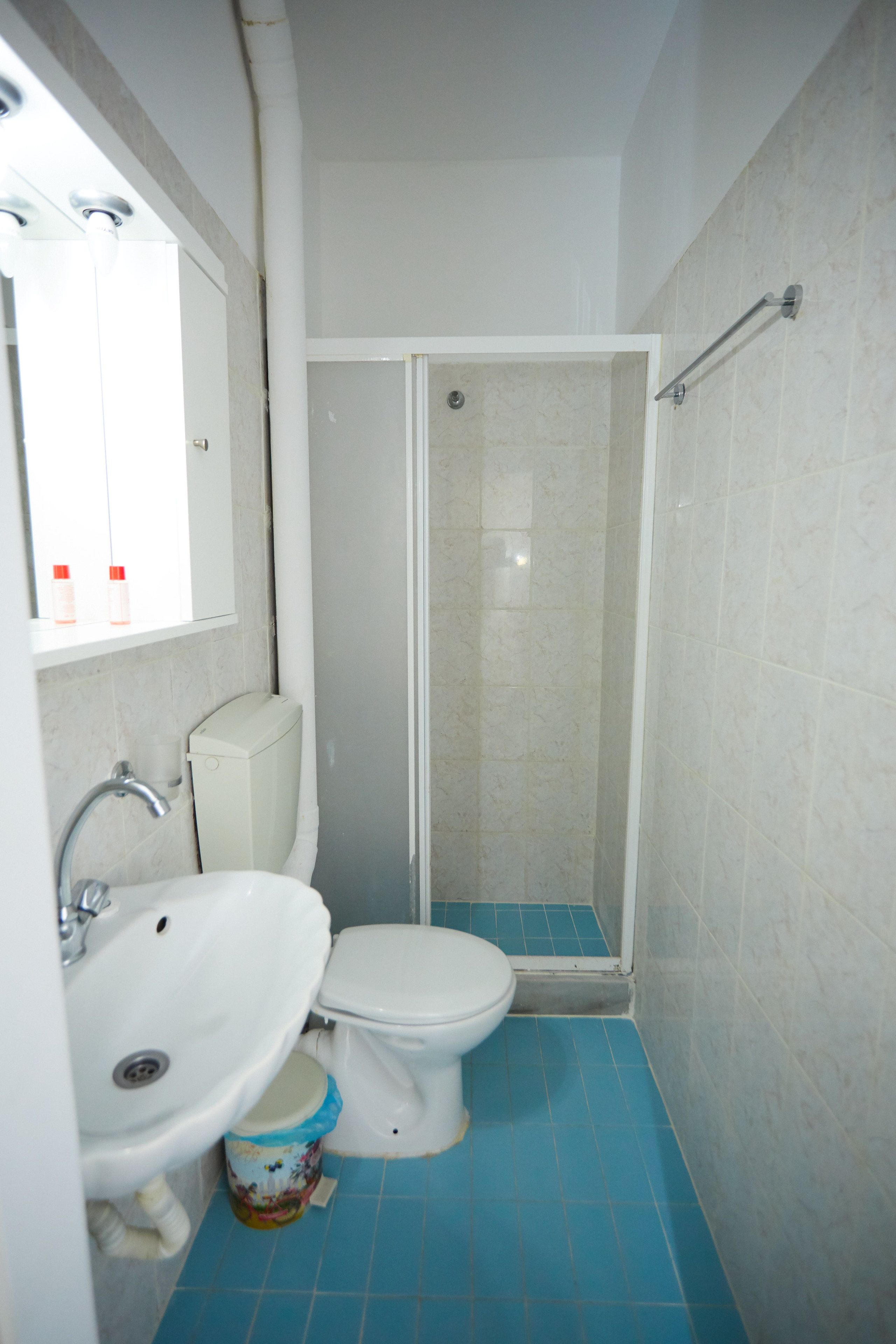 A bathroom with a white sink, toilet, and shower enclosure.
