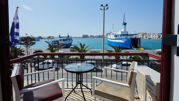A balcony with a table and chairs, overlooking a marina with boats and a clear sky. - Aegean Sea Rooms (Chios)