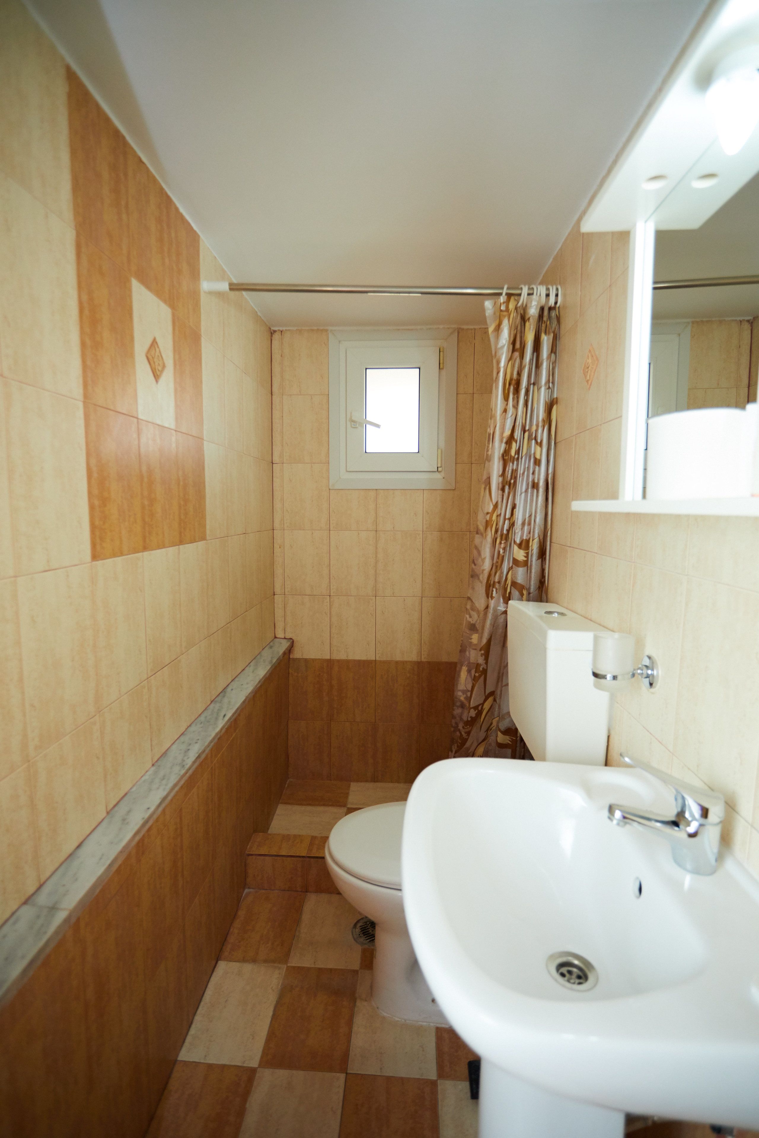 Baño con inodoro, lavamanos y cortina de ducha.