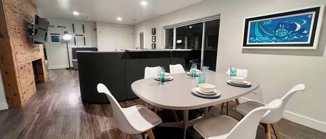 Un comedor moderno con una mesa redonda para cuatro personas, sillas blancas y un banco acolchado negro.
