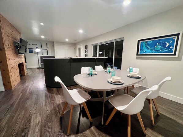 A modern dining area with a round table set for four, white chairs, and a black cushioned bench. - Ski, Hike, Hottub + Ping-Pong & Pool. Fun Open Concept - sleeps 14 - great price (Salt Lake City)