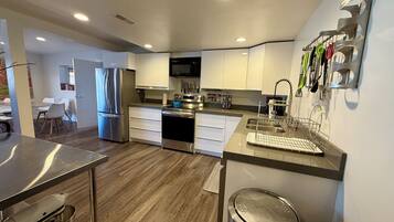 A modern kitchen with stainless steel appliances, white cabinetry, and a built-in microwave.