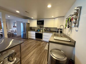 A modern kitchen with stainless steel appliances, white cabinetry, and a built-in microwave. - Ski, Hike, Hottub + Ping-Pong & Pool. Fun Open Concept - sleeps 14 - great price (Salt Lake City)
