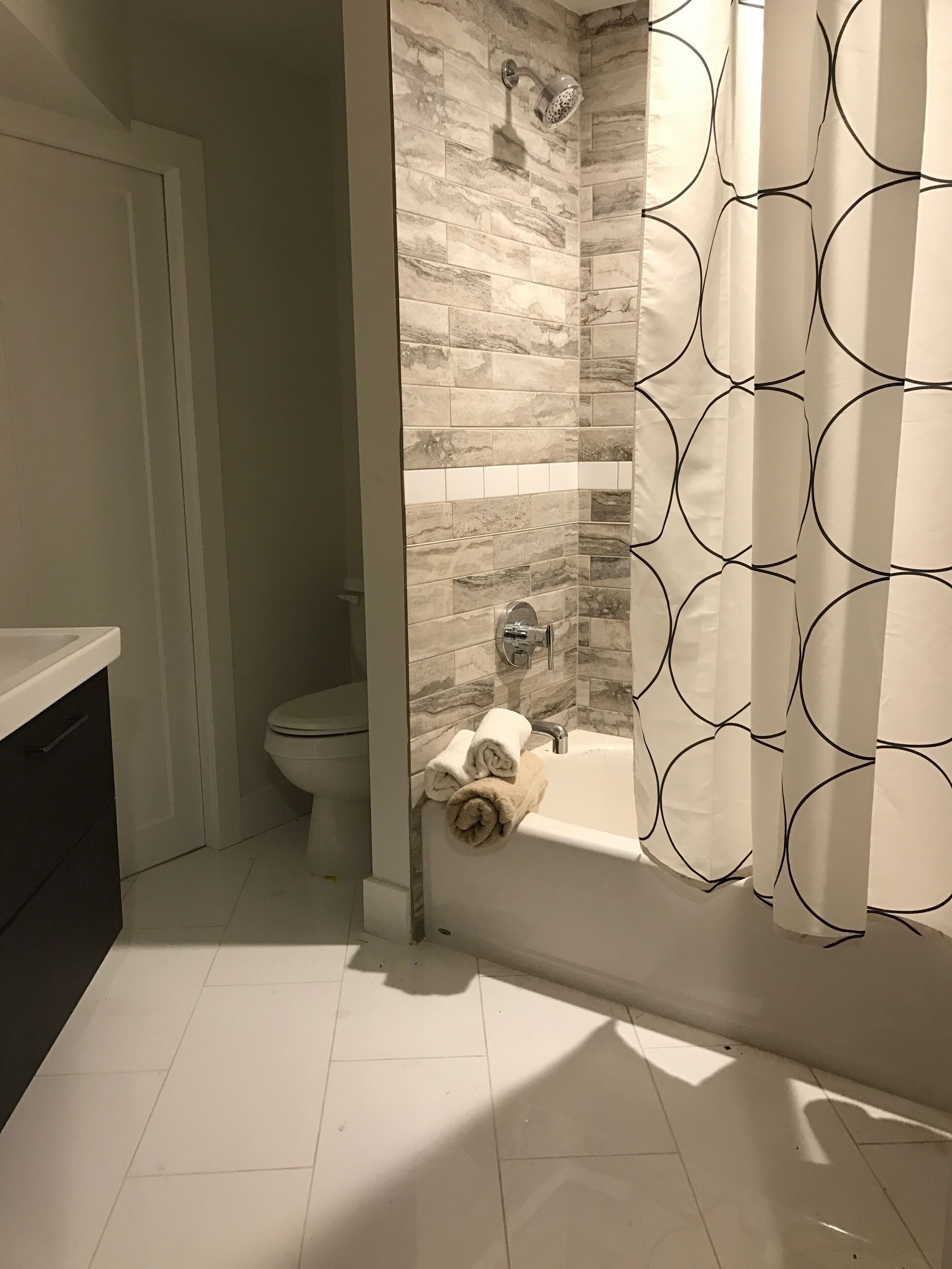 Un baño con inodoro, ducha con cabezal de lluvia y bañera con una toalla sobre el borde.