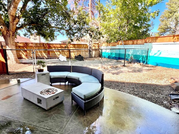 A patio with a curved sofa and a coffee table, surrounded by a wooden fence and trees. - Ski, Hike, Hottub + Ping-Pong & Pool. Fun Open Concept - sleeps 14 - great price (Salt Lake City)