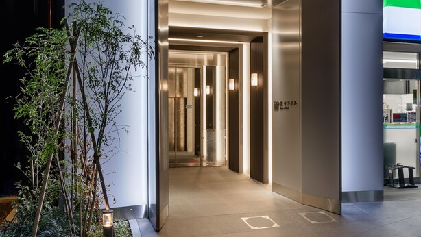 A modern elevator entrance with a glass door, a hallway with a light fixture, and a sign indicating the elevator's location. -  Henn na Hotel Premier Tokyo Asakusa Tawaramachi (Tokyo)