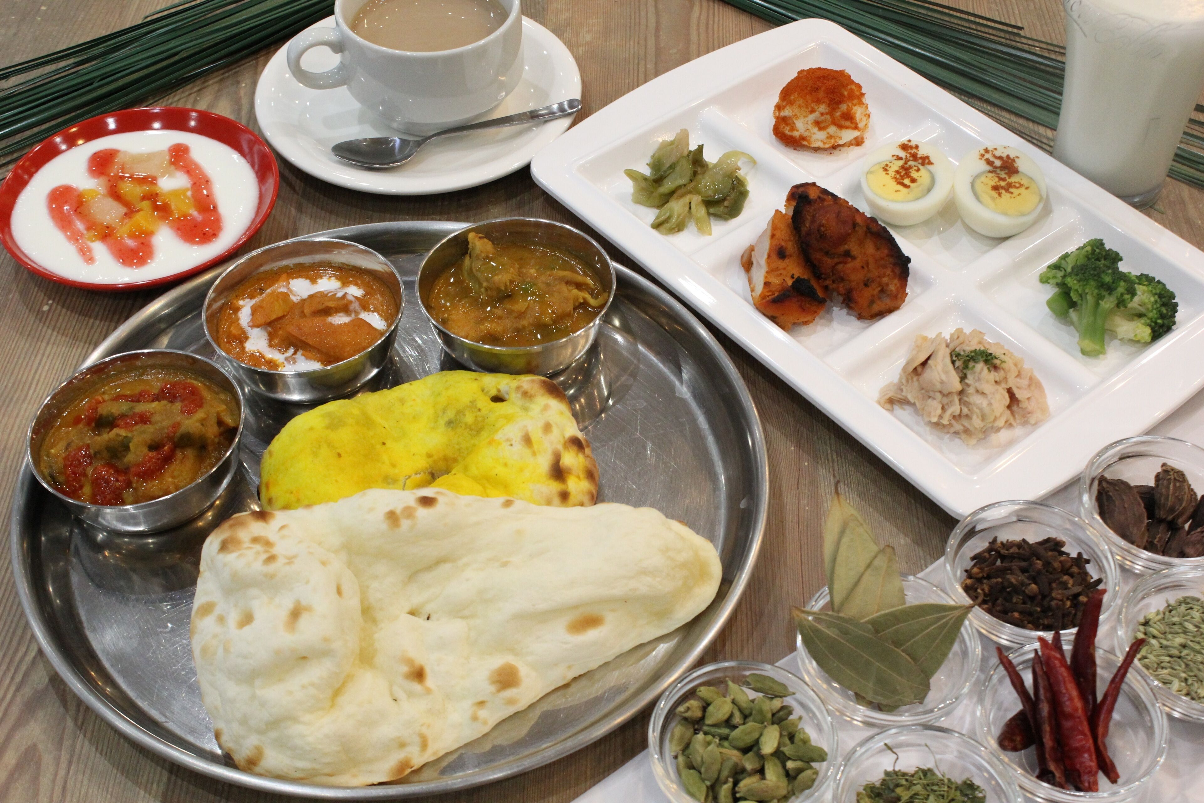 A meal with various dishes, including flatbread, curries, and a plate with eggs and vegetables.