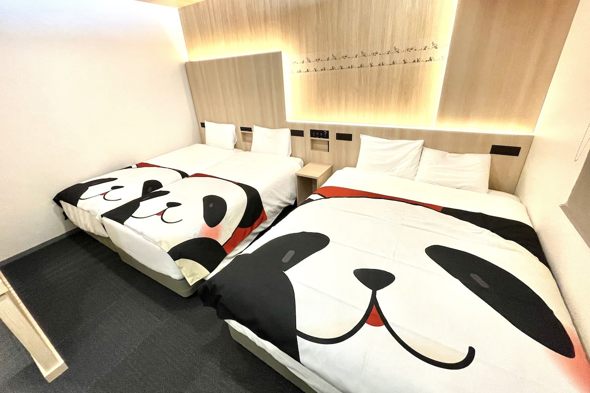 A hotel room with two beds, each with a unique dog-themed bedspread.
