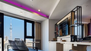 A modern hotel room with a sofa, a desk, a chair, and a large window offering a city view. -  Henn na Hotel Premier Tokyo Asakusa Tawaramachi (Tokyo)