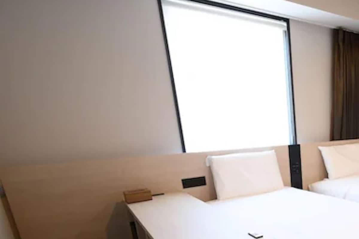 A hotel room with a bed, a desk, and a chair.
