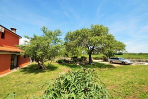 Stroll through the tranquil garden, surrounded by lush trees and shrubs, with a driveway leading to a serene escape.