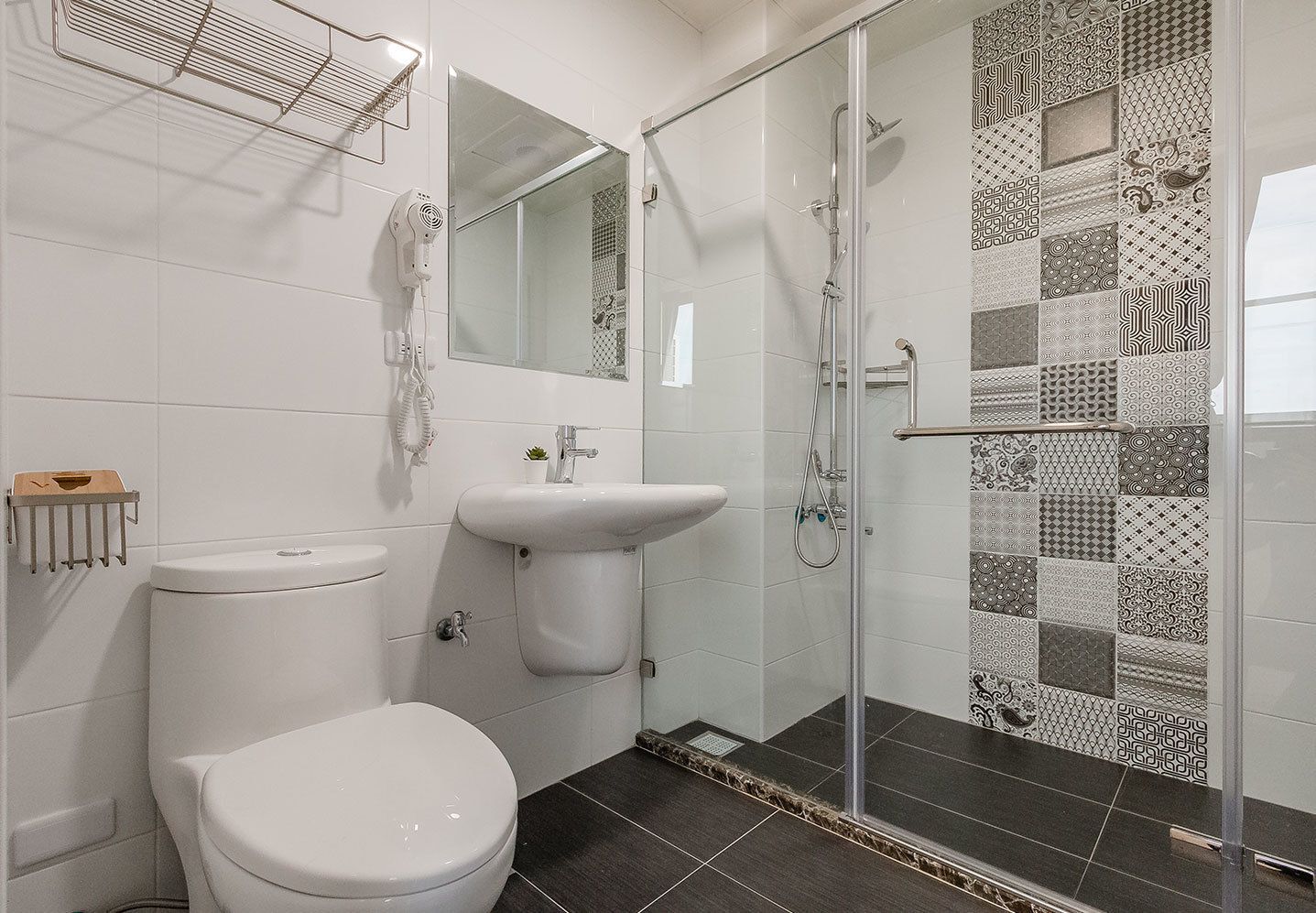 Un baño con inodoro, lavabo y cabina de ducha con mampara de vidrio.