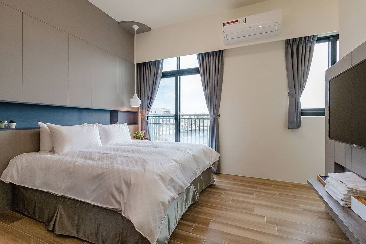 Una habitación de hotel moderna con una cama grande, un televisor y un balcón con vistas.