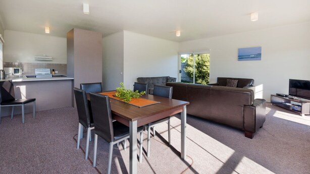 A modern living space with a dining area, kitchen, and seating area. - Julieanne (Port Fairy)