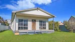A single-story house with a front porch, a wooden door, and a large window. - Julieanne (Port Fairy)