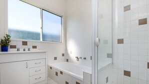 A bathroom with a bathtub, a shower, and a window. - Julieanne (Port Fairy)