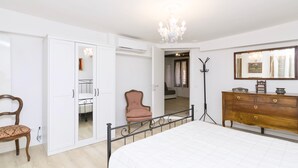 A bedroom with a bed, a wooden dresser, a chair, a wardrobe, and a mirror. - Ca' Alberto Apartments 1 (Venice)