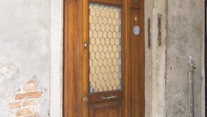 A wooden door with a glass panel, a metal handle, and a brass lock. - Ca' Alberto Apartments 1 (Venice)