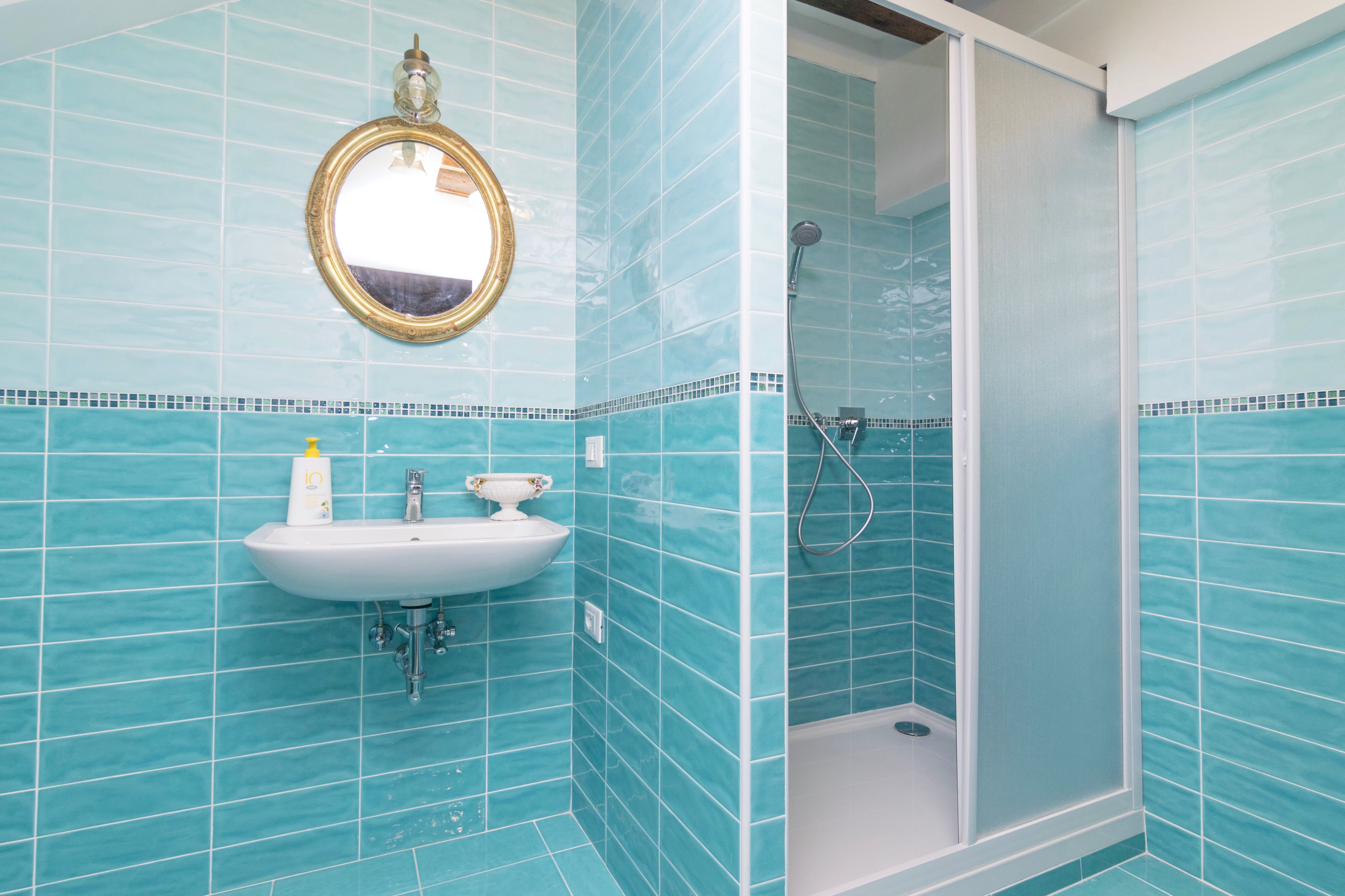 Un baño con lavamanos, espejo y ducha.