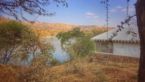 A tented accommodation by a lake with a view of hills.