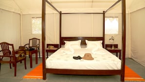 A four-poster bed with a canopy, wooden headboard, and footboard, flanked by two nightstands with lamps.