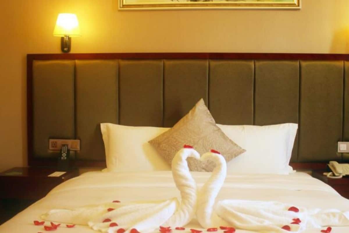 Habitació d'hotel amb un llit ben fet, un coixí i un quadre penjat a la paret.