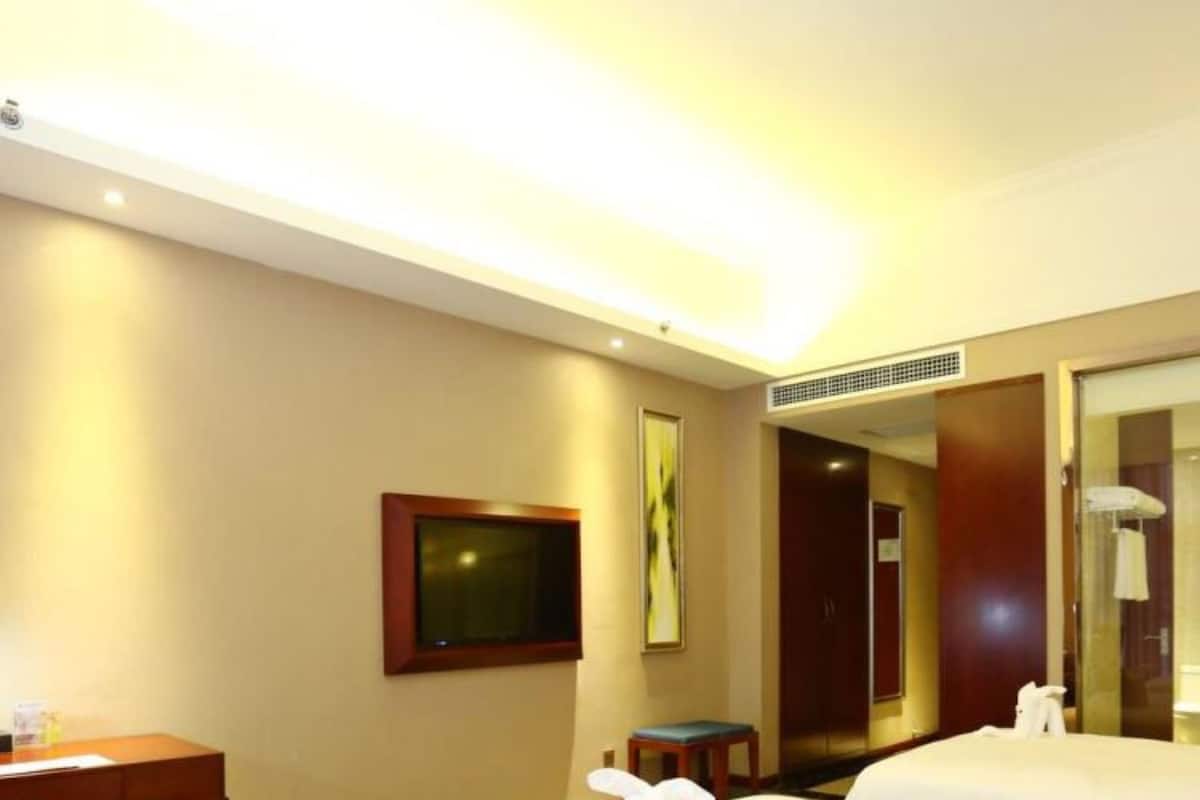 Habitació d'hotel amb dos llits, una taula de treball, una cadira, una televisió i un mirall.